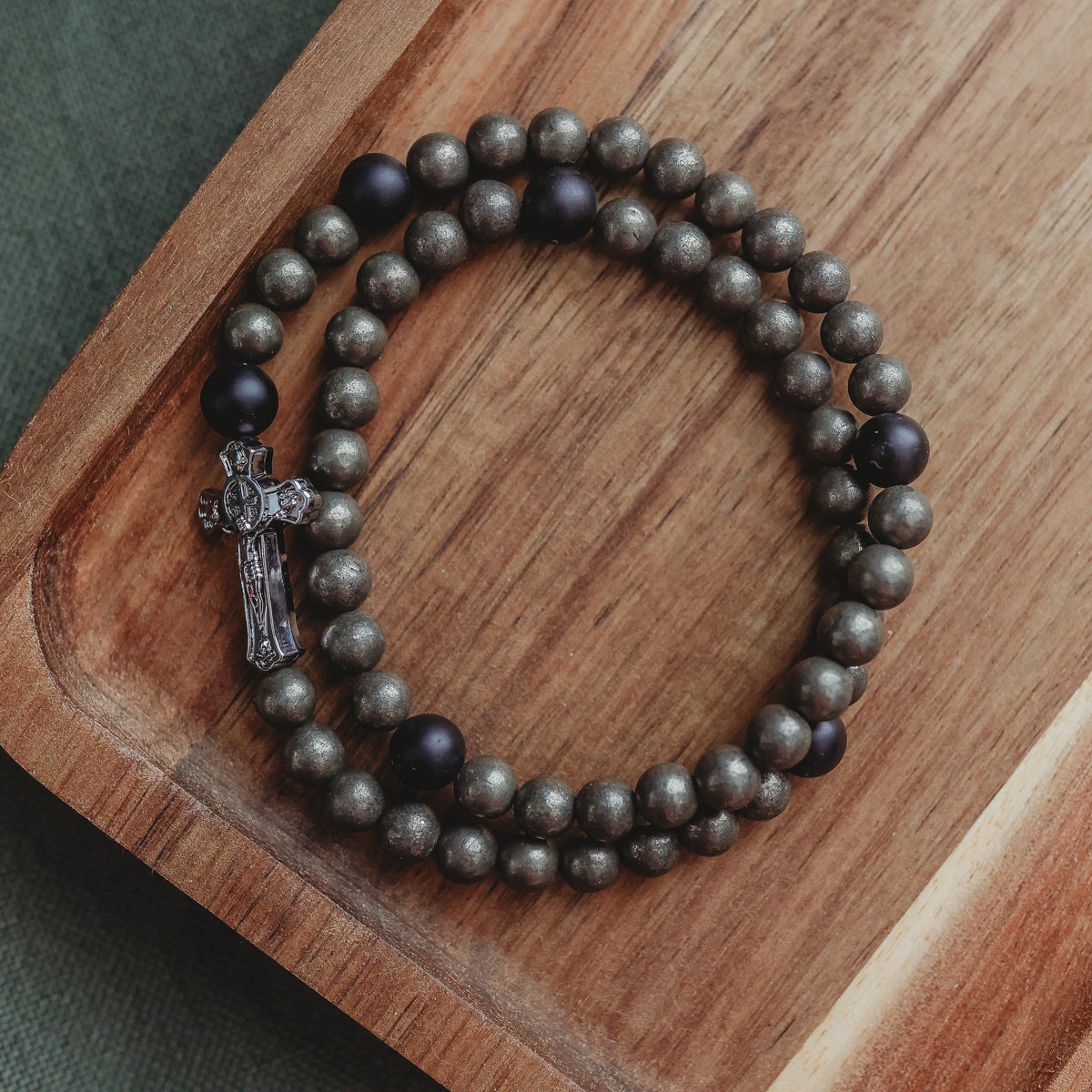 Beaded bracelet with a cross on a wooden tray